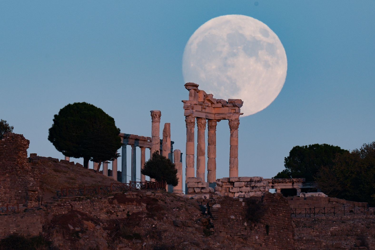 The full moon rises behind the ancient Acropolis in the Bergama district of Izmir, Turkey.